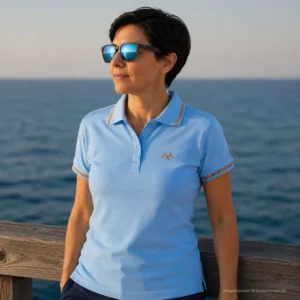 Polo celeste mujer con banderas cruzadas de España bordadas en el pecho y bandera integrada en cuello y mangas