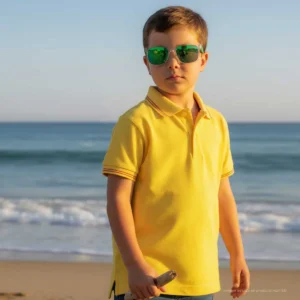 Niño con polo amarillo y detalles de la bandera de España junto al mar