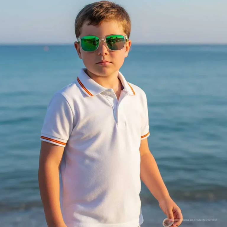 Niño con polo blanco y bandera de España frente al mar