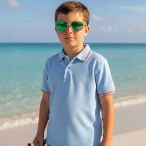 Niño con polo celeste y detalles de la bandera de España junto al mar