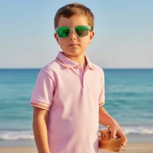 Niño con polo rosa y bandera de España en la playa